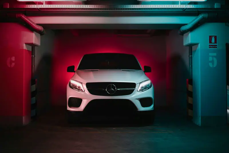 Weisser SUV mit eingeschaltetem Licht in einer beleuchteten Garagenbox